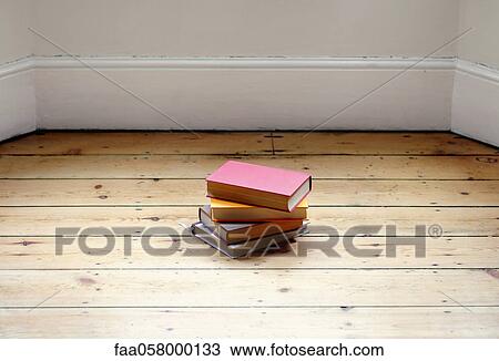 Stock Image - Books stacked on hardwood floor. Fotosearch