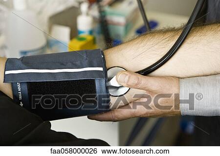 Stock Photograph - Doctor checking patient's blood pressure. Fotosearch