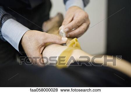 Stock Photo - Doctor giving patient an injection, cropped. Fotosearch