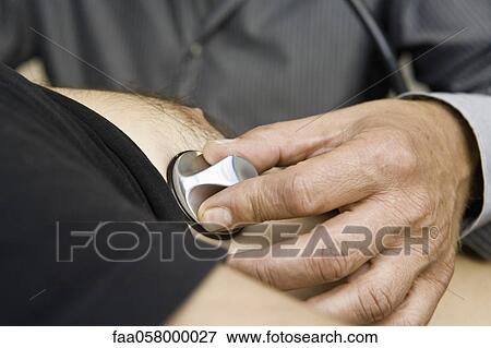 Doctor listening to patient's chest with stethoscope, cropped View Large Photo Image Stock Photo - Doctor listening to patient's chest with stethoscope, cropped. Fotosearch