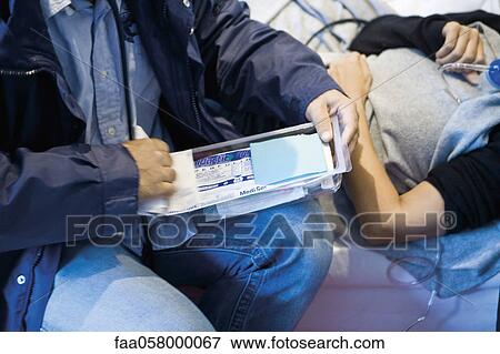 Doctor opening medical supplies to treat patient, cropped View Large Photo Image Stock Photo - Doctor opening medical supplies to treat patient, cropped. Fotosearch