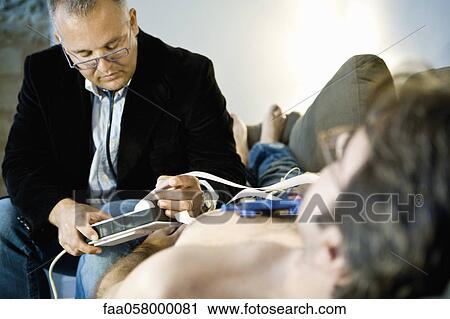 Doctor performing portable EKG (electrocardiogram) on patient in home View Large Photo Image Stock Image - Doctor performing portable EKG (electrocardiogram) on patient in home. Fotosearch