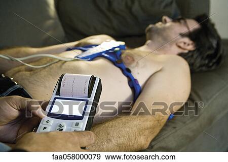 Stock Photo - Doctor performing portable EKG (electrocardiogram) on patient in home. Fotosearch