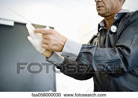 Doctor putting on latex gloves View Large Photo Image Stock Image - Doctor putting on latex gloves. Fotosearch