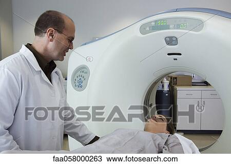 Stock Image - Doctor reassuring nervous female patient preparing to undergo CAT scan. Fotosearch
