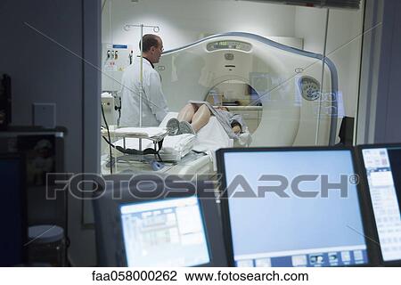 Stock Image - Doctor talking to female patient preparing to undergo CAT scan. Fotosearch