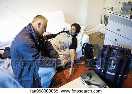 Emergency on-call doctor administering oxygen to patient in home View Large Photo Image Stock Photography - Emergency on-call doctor administering oxygen to patient in home. Fotosearch