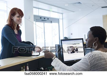 Female customer handing credit card to receptionist View Large Photo Image Stock Image - Female customer handing credit card to receptionist. Fotosearch