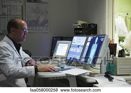 Stock Photo - Male doctor evaluating medical exam result on computer monitor. Fotosearch