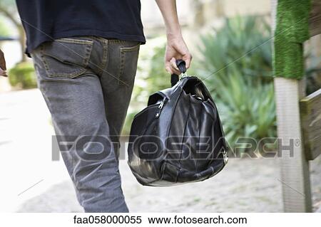 Stock Photography - Man carrying bag, rear view. Fotosearch