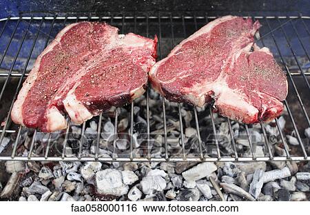 Stock Photograph - Uncooked T-bone steaks on barbecue grill. Fotosearch