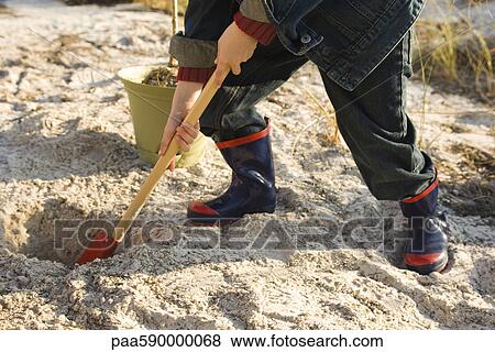 Boy digging hole in sand View Large Photo Image Stock Photo - Boy digging hole in sand. Fotosearch