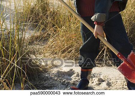 Stock Image - Boy digging with shovel in sand. Fotosearch