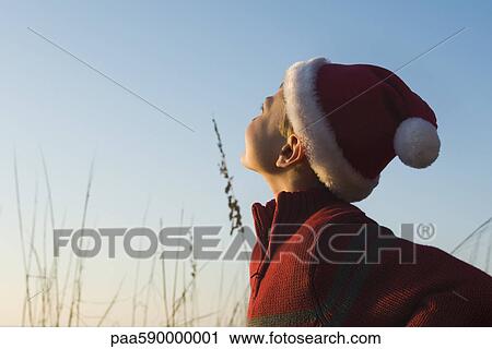 Boy wearing Santa hat outdoors, contemplatively looking away View Large Photo Image Stock Image - Boy wearing Santa hat outdoors, contemplatively looking away. Fotosearch