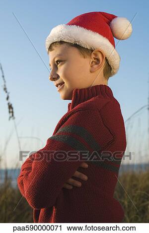 Boy wearing Santa hat outdoors, contemplatively looking away View Large Photo Image Stock Image - Boy wearing Santa hat outdoors, contemplatively looking away. Fotosearch