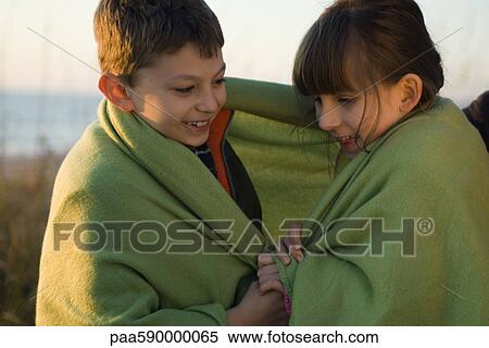 Stock Photography - Children wrapped together in blanket outdoors, portrait. Fotosearch