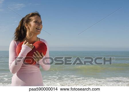 Preteen girl at beach holding stuffed heart-shaped toy contemplating love View Large Photo Image Picture - Preteen girl at beach holding stuffed heart-shaped toy contemplating love. Fotosearch