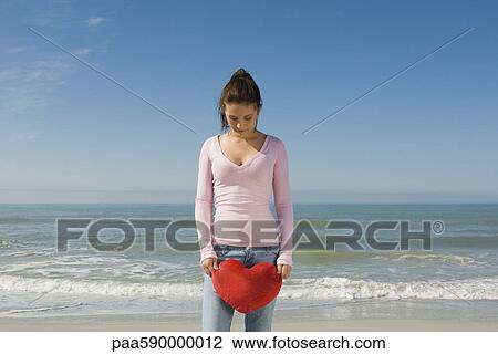 Preteen girl at beach holding stuffed heart-shaped toy, looking down in disappointment View Large Photo Image Stock Image - Preteen girl at beach holding stuffed heart-shaped toy, looking down in disappointment. Fotosearch