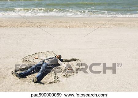 Stock Photo - Preteen girl at beach making snow angel in sand. Fotosearch