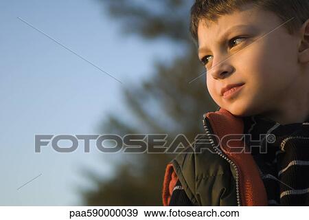Young boy outdoors contemplatively looking away View Large Photo Image Stock Photo - Young boy outdoors contemplatively looking away. Fotosearch