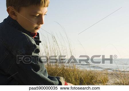 Stock Photography - Young boy outdoors contemplatively looking away. Fotosearch