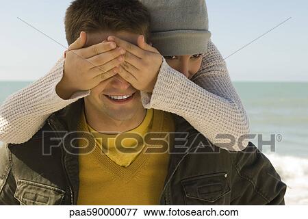 Young couple enjoying winter's day outing to beach, girl surprising boyfriend from behind View Large Photo Image Stock Photo - Young couple enjoying winter's day outing to beach, girl surprising boyfriend from behind. Fotosearch