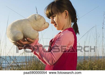 Picture - Young girl face to face with stuffed toy polar bear cub. Fotosearch