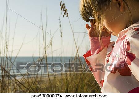 Picture - Young girl outdoors, sea in background. Fotosearch