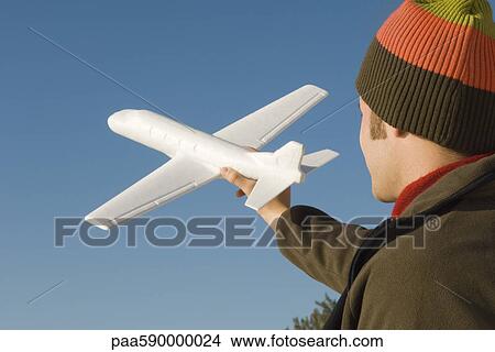 Young man at beach holding aloft toy airplane View Large Photo Image Picture - Young man at beach holding aloft toy airplane. Fotosearch