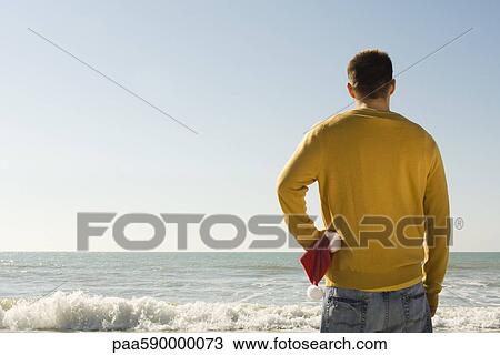 Young man at beach looking at view View Large Photo Image Stock Image - Young man at beach looking at view. Fotosearch