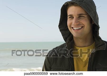 Stock Photo - Young man at beach, portrait. Fotosearch