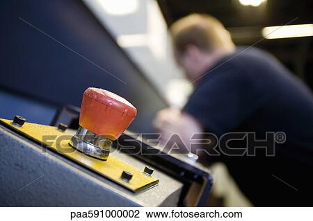 Stock Image - Emergency stop knob on machine in carpet tile factory. Fotosearch