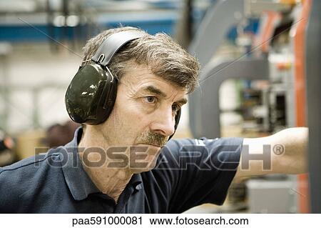Factory worker wearing protective headphones View Large Photo Image Stock Image - Factory worker wearing protective headphones. Fotosearch
