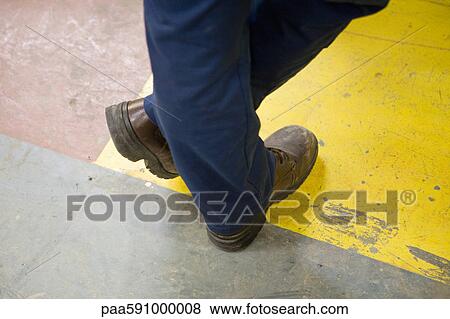 Factory worker wearing protective boots, standing with legs crossed at ankle, cropped View Large Photo Image Stock Photo - Factory worker wearing protective boots, standing with legs crossed at ankle, cropped. Fotosearch