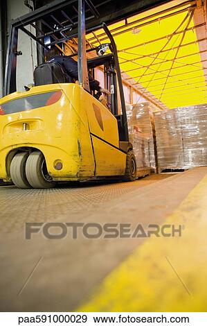 Forklift operator loading wrapped pallets of cardboard boxes onto trailer in warehouse View Large Photo Image Stock Photo - Forklift operator loading wrapped pallets of cardboard boxes onto trailer in warehouse. Fotosearch