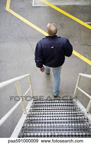 Stock Photo - Man going down metal stairs. Fotosearch