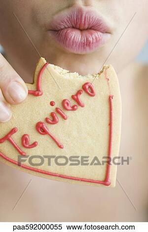 Woman eating heart-shaped cookie, puckering lips View Large Photo Image Stock Photography - Woman eating heart-shaped cookie, puckering lips. Fotosearch