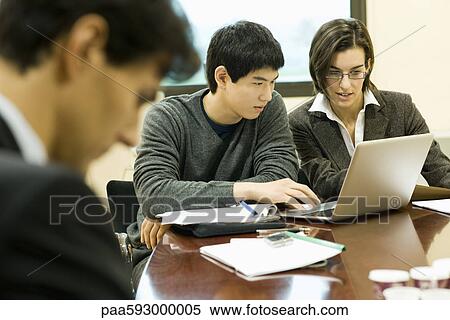 Stock Photography - Colleagues working together on laptop computer. Fotosearch