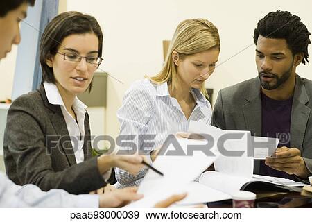 Stock Photo - Executives discussing documents in meeting. Fotosearch