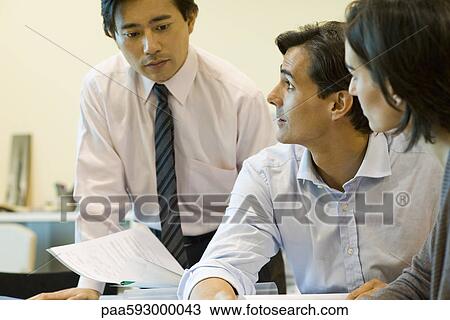 Stock Image - Executives discussing documents. Fotosearch