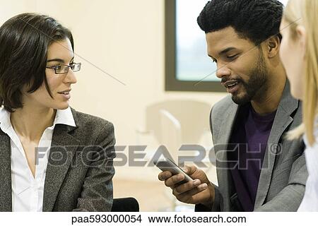 Executives in meeting, one text messaging with cell phone View Large Photo Image Picture - Executives in meeting, one text messaging with cell phone. Fotosearch