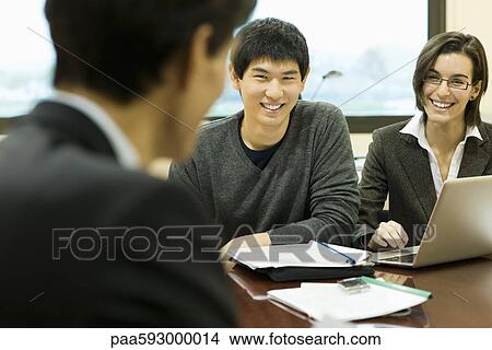 Picture - Executives in meeting, smiling at each other. Fotosearch