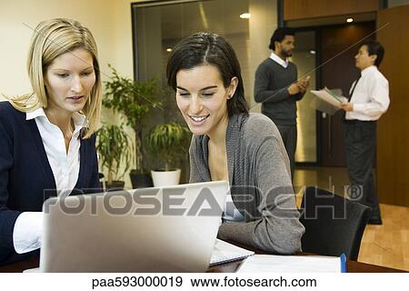Stock Photo - Executives working together on laptop computer. Fotosearch