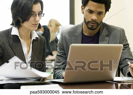 Stock Photography - Executives working together on laptop computer. Fotosearch