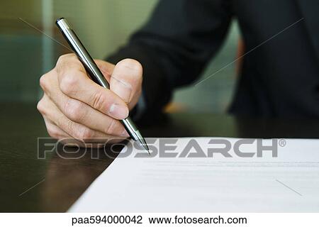 Stock Image - Businessman signing paperwork, cropped. Fotosearch