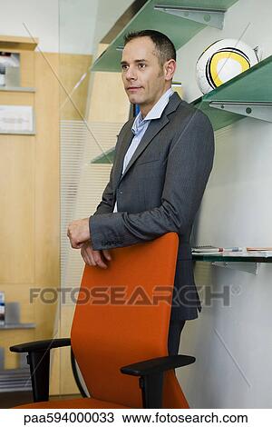 Businessman standing behind office chair, portrait View Large Photo Image Stock Image - Businessman standing behind office chair, portrait. Fotosearch