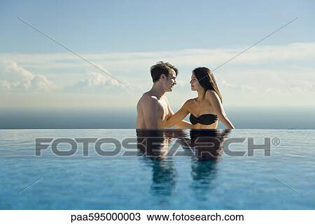 Stock Image - Couple relaxing by infinity pool. Fotosearch