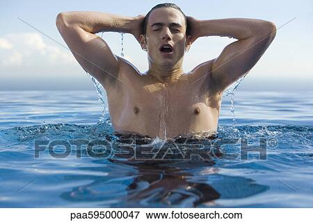 Stock Photo - Man in water, hands behind head. Fotosearch