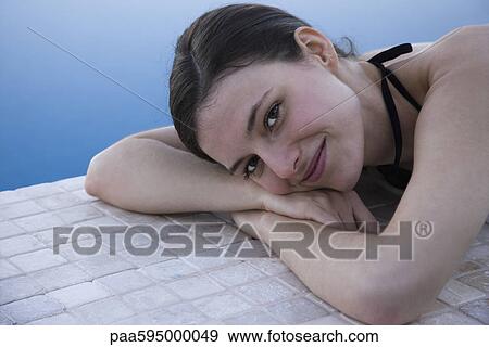 Stock Photo - Woman lying beside pool, portrait. Fotosearch