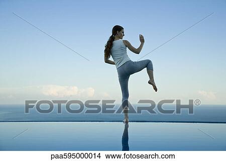 Woman practicing Tai Chi Chuan on edge of infinity pool View Large Photo Image Picture - Woman practicing Tai Chi Chuan on edge of infinity pool. Fotosearch